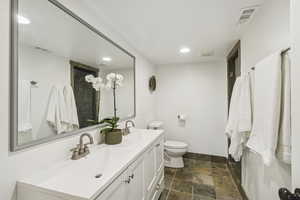 Bathroom with double vanity, recessed lighting, dark stone finish floors, and a shower