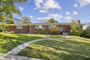 Single story home with brick siding, a front lawn, a chimney, and a mountain view