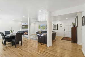 Dining area with recessed lighting, light wood-style flooring, a glass covered fireplace, and a ceiling fan