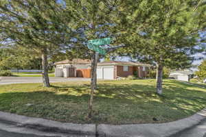Ranch-style home featuring brick siding, driveway, an attached garage, and an outbuilding