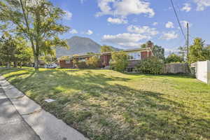 View of front of property with a mountain view, brick siding, and a chimney