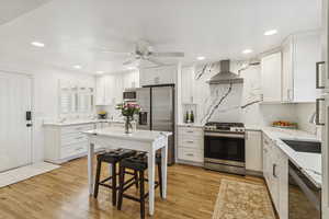 Kitchen with stainless steel appliances, light stone counters, white cabinetry, and recessed lighting
