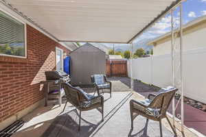 Fenced backyard with a storage shed, a patio, area for grilling, and a mountain view