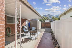 Fenced backyard with a storage shed, a mountain view, a patio, and grilling area