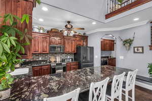 Kitchen with dark stone counters, decorative backsplash, ornamental molding, a peninsula, and appliances with stainless steel finishes