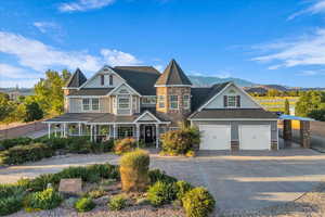 View of front of house featuring stone siding, a porch, driveway, a garage, and a mountain view