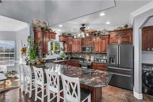 Kitchen with ornamental molding, appliances with stainless steel finishes, dark stone counters, washer / dryer, and backsplash