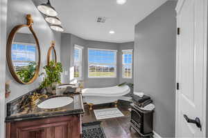 Full bathroom featuring a freestanding tub, double vanity, recessed lighting, and stone tile flooring
