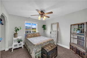 Bedroom with dark colored carpet and a ceiling fan