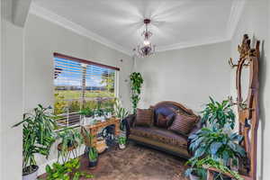 Living area featuring ornamental molding and a chandelier