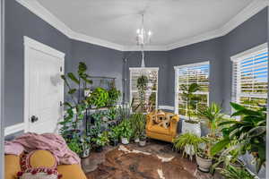 Living area with ornamental molding and a chandelier