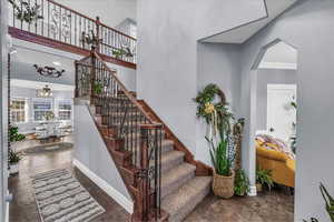 Stairway featuring a towering ceiling, ornamental molding, and ceiling fan