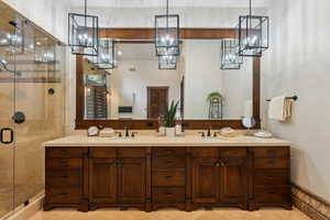 Full bath with a stall shower, double vanity, and light tile patterned floors
