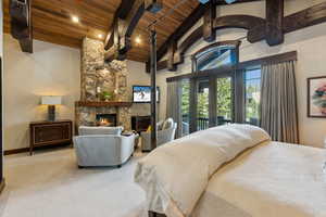 Carpeted bedroom with a wood ceiling with exposed beams, a fireplace, access to exterior, french doors, and high vaulted ceiling