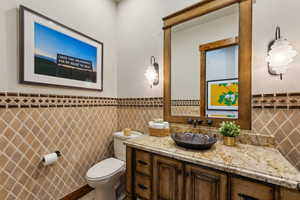 Half bathroom with tile walls, vanity, and wainscoting