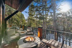 Wooden terrace with a fire pit and view of scattered trees