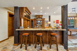 Indoor wet bar with open shelves, light stone counters, light stone finish flooring, recessed lighting, and pool table
