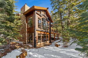 Snow covered property featuring a chimney and a balcony