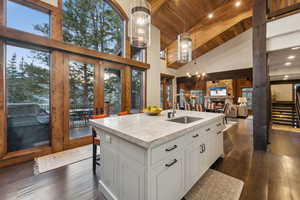 Kitchen featuring pendant lighting, french doors, a stone fireplace, an island with sink, and high vaulted ceiling