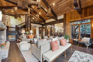 Living area with high vaulted ceiling, a wood ceiling with exposed beams, dark wood-type flooring, and stairway