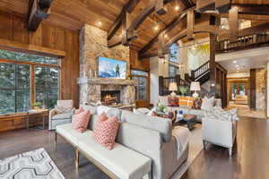 Living room featuring a wood ceiling with exposed beams, high vaulted ceiling, a fireplace, dark wood-style floors, and stairway
