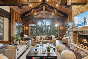 Living area with high vaulted ceiling, a fireplace, wood-type flooring, a wood ceiling with exposed beams, and wood walls