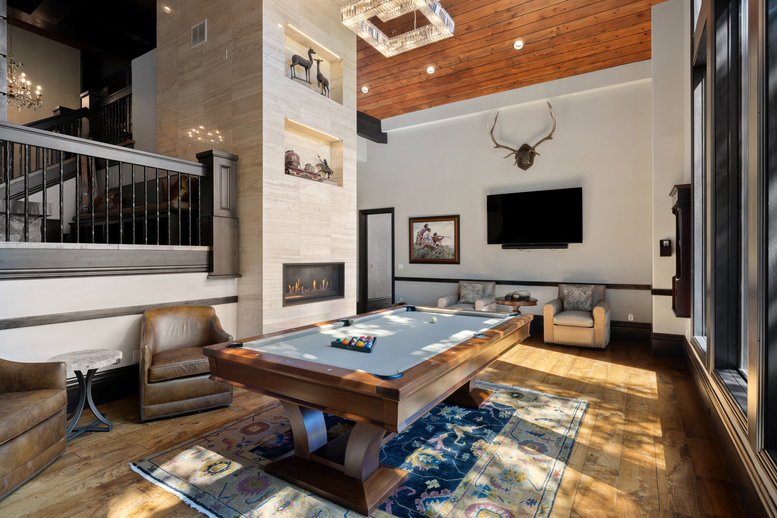 Game room featuring hardwood / wood-style floors, billiards table, a high ceiling, a fireplace, and a chandelier