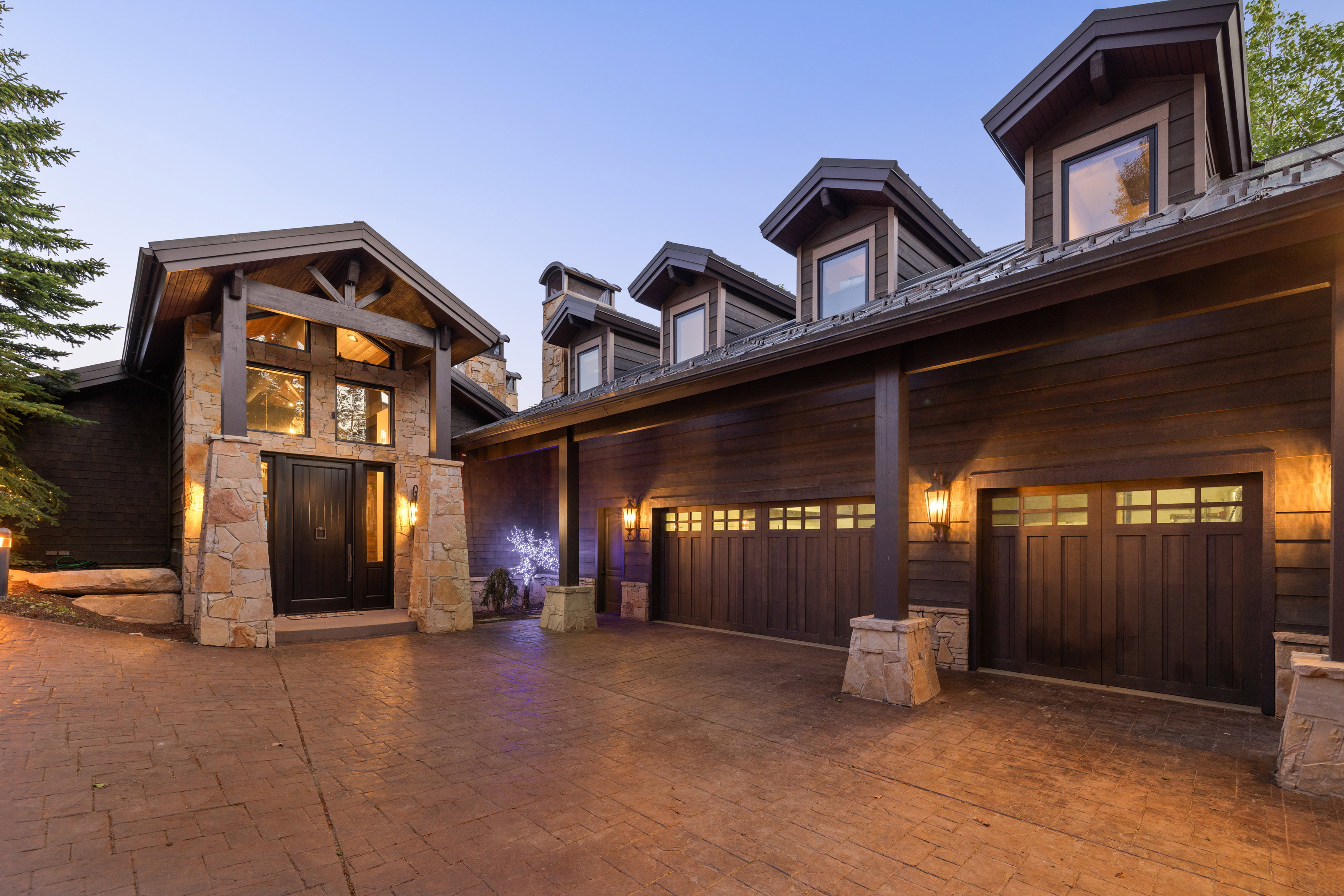View of front of home with decorative driveway, stone siding, and a garage