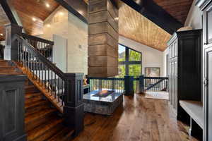 Stairway with high vaulted ceiling, hardwood / wood-style floors, and a wood ceiling with exposed beams