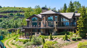 Rear view of house with a standing seam roof, stone siding, a metal roof, a patio, and a chimney