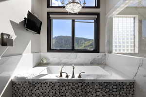 Bathroom featuring a garden tub, plenty of natural light, and a chandelier