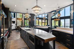 Kitchen featuring dark cabinets, stone tile floors, appliances with stainless steel finishes, healthy amount of natural light, and recessed lighting