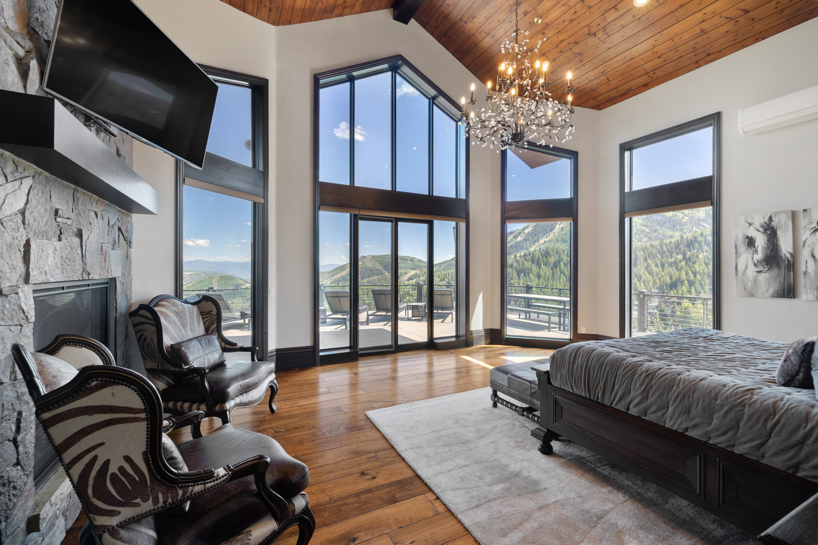 Bedroom featuring wooden ceiling, hardwood / wood-style floors, high vaulted ceiling, a fireplace, and a chandelier