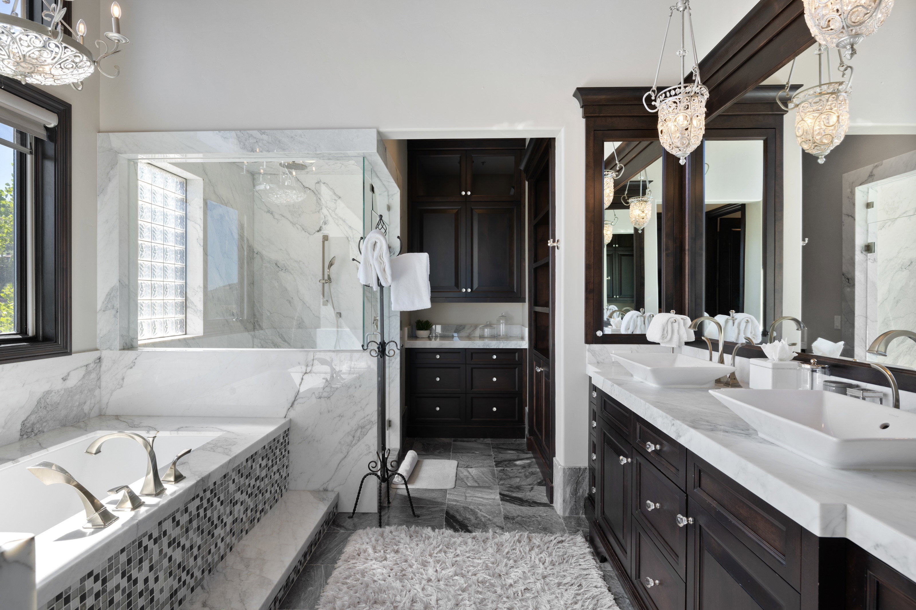 Bathroom with a chandelier, double vanity, a marble finish shower, a garden tub, and dark marble finish flooring