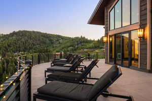 Wooden deck featuring a patio area, a mountain view, and a wooded view