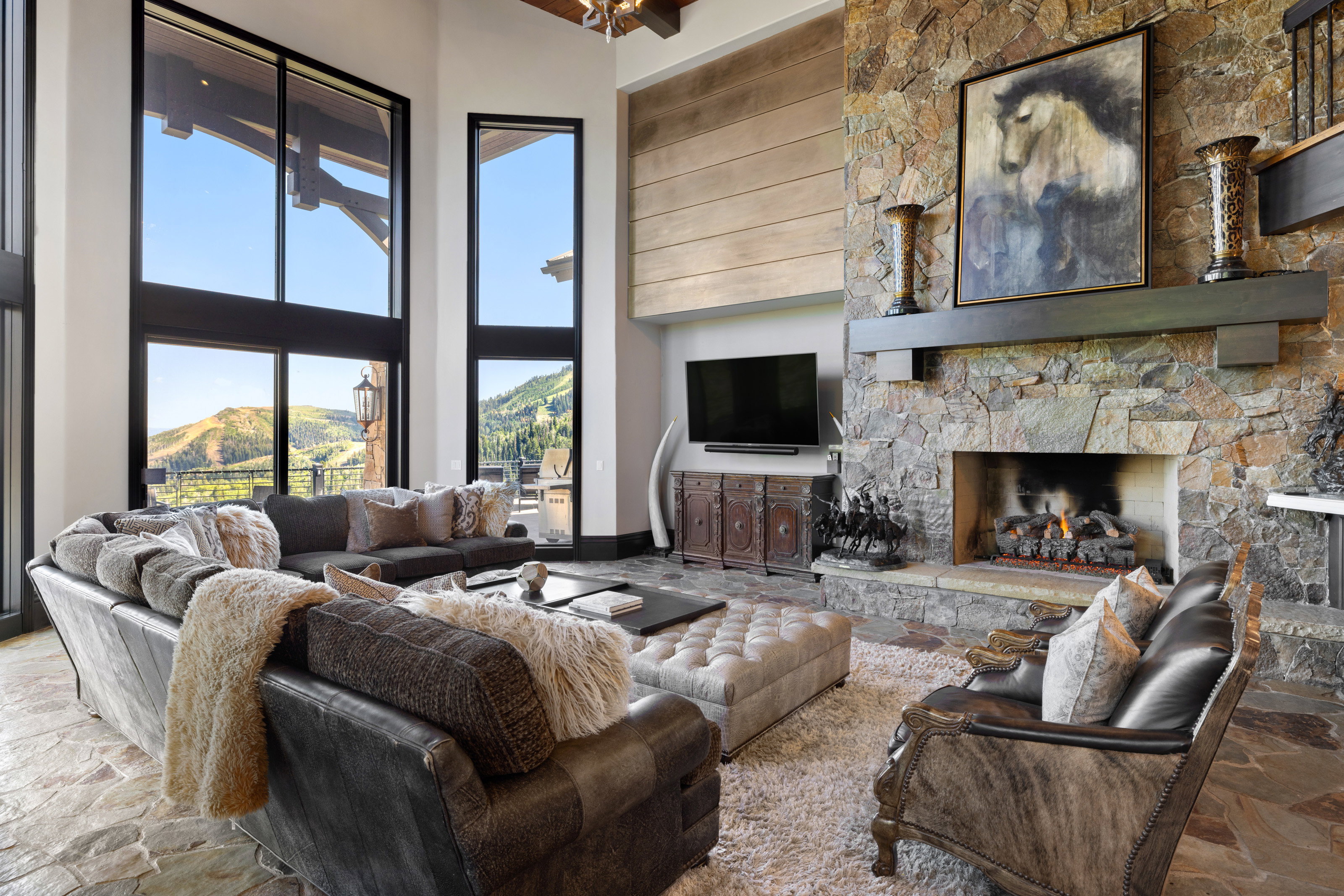 Living room featuring stone floors, a fireplace, and a towering ceiling