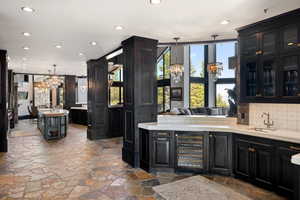 Bar with a chandelier, recessed lighting, beverage cooler, dark cabinets, and decorative light fixtures