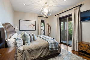 Bedroom with dark wood-style flooring, recessed lighting, a chandelier, and access to exterior
