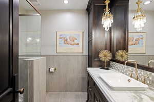 Bathroom featuring vanity, a wainscoted wall, recessed lighting, and tile walls