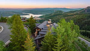 Aerial view of property and surrounding area with a forest and a water and mountain view