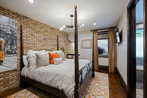 Bedroom featuring brick wall, dark wood finished floors, recessed lighting, and an accent wall