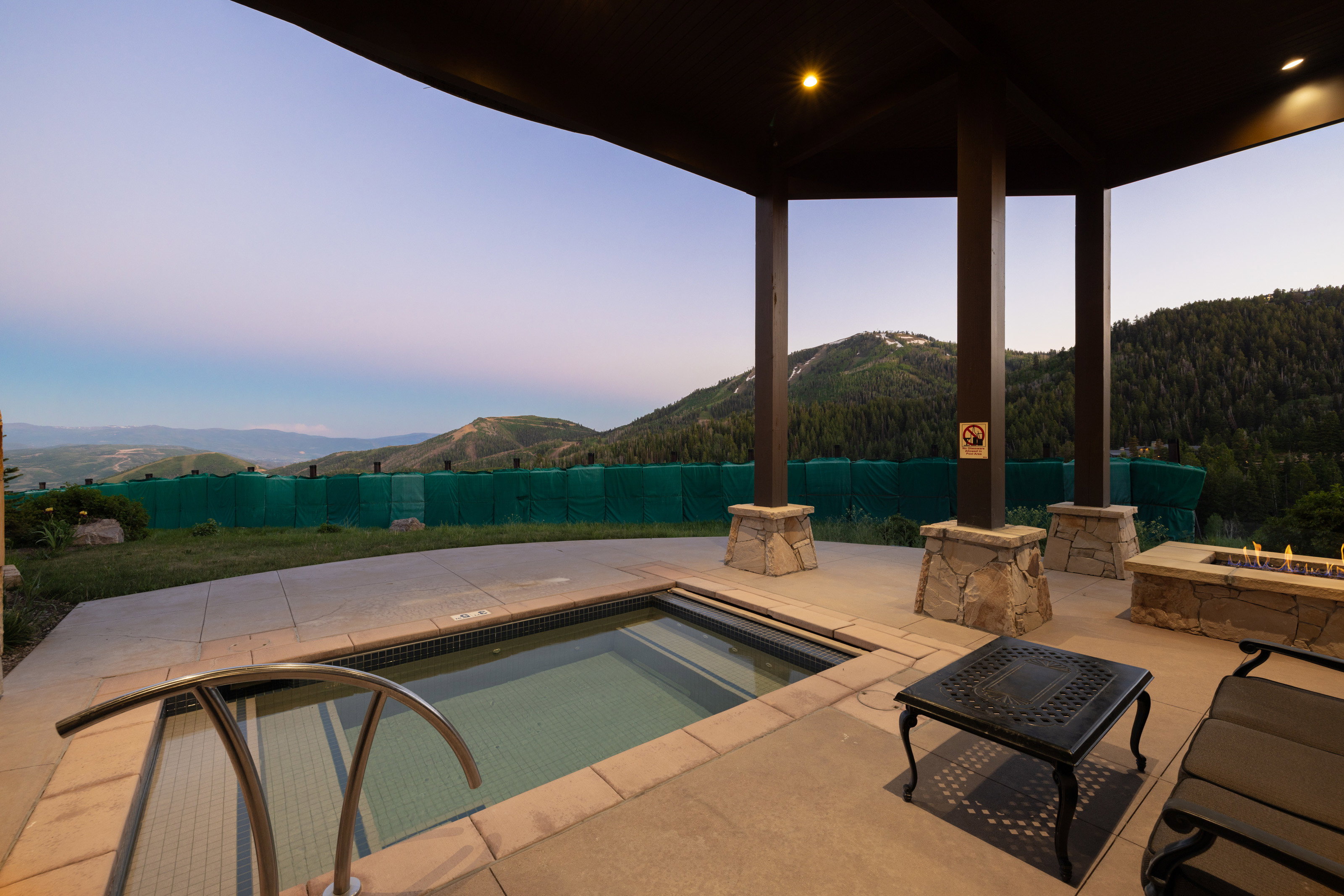Swimming pool with a mountain view, a patio, a fire pit, a jacuzzi, and a wooded view
