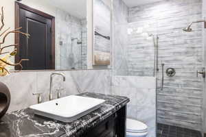 Full bath featuring tile walls, a stall shower, vanity, and tasteful backsplash