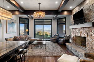 Living area with beamed ceiling, dark wood-style floors, a fireplace, a chandelier, and recessed lighting