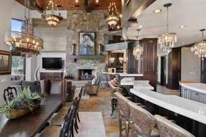 Dining area with a chandelier, a fireplace, stone tile floors, recessed lighting, and a high ceiling