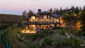 Back of property at dusk with a chimney, a patio, a metal roof, a standing seam roof, and a yard