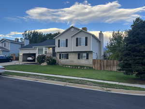 View of front facade with brick siding, a chimney, concrete driveway, and a garage