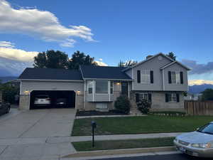 Tri-level home with driveway, a garage, a mountain view, and brick siding