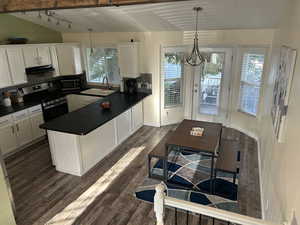 Kitchen featuring white cabinetry, stainless steel appliances, hanging light fixtures, and dark wood-style floors