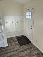 Doorway to outside featuring wood finished floors, a decorative wall, and wainscoting